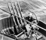 Gunner's Mate Vonzo Smith beside a quad 1.1" anti-aircraft mount aboard Enterprise in early 1942.