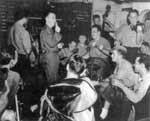 Men drown jitters in music in the VF(N)-90 Ready Room, the night before the Tokyo Raids.