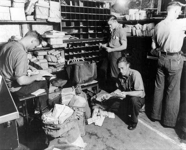 Crewmen sort newly-arrived mail in Enterprise CV-6's Post Office.