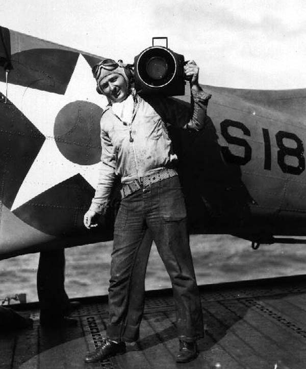 Photographer's Mate Robert F. Read, standing with an aerial camera in front of a Scouting Six plane.