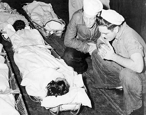 A wounded sailor of the Big E gets encouragement and comfort from two of his shipmates.